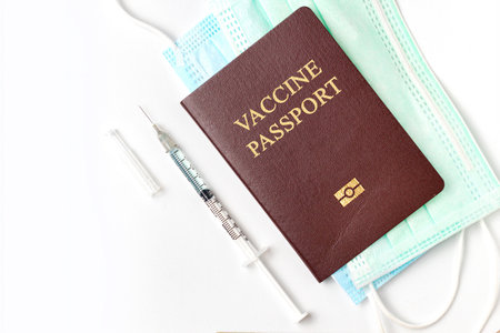 Passport with medical vaccine syringe needle and face mask on white background. Vaccination passport is concept of immune travel to protect from Covid-19 virus pandemic.の写真素材