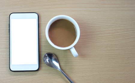 white coffee mug and blank screen of smartphone on a brown wooden floor and have copy space for design in you concept.の写真素材