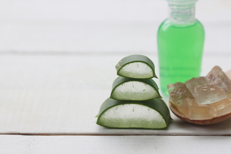 Stacked slice Aloe Vera and green bottle gel placed on a white wooden floor and have copy space for your work.の写真素材