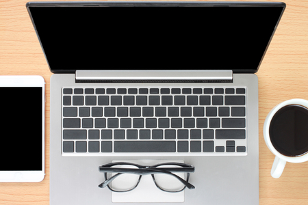 Blank Notebook and smartphone near coffee mugs are placed on a wooden desk,Topview to design in your work.の写真素材