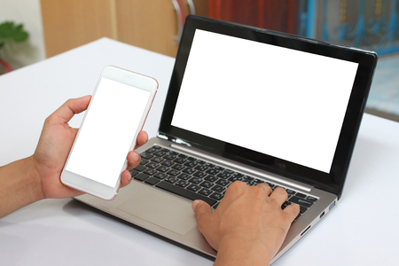 Hands of a businessman holding an empty smartphone and have blank notebook Laptop have white screen for a design in your business concept.の写真素材