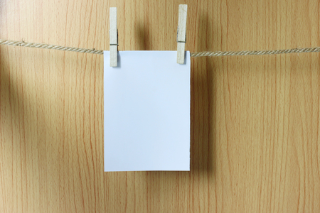 Blank paper hangs on the brown rope with Wooden paper clips on wood background for design in your work concept.の写真素材