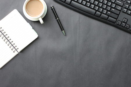 Black desk with coffee cup, keyboard, notebook,and pen placed in the office.Top view and have copy space the concept in your work.の写真素材