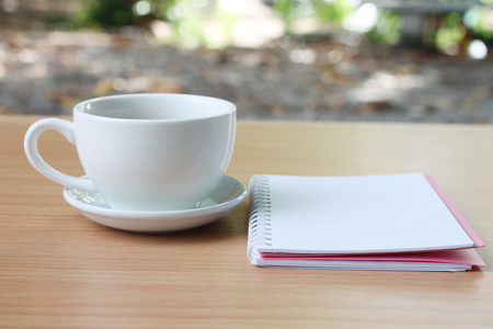 Coffee cup and notebook are placed on a brown wooden table and have copy space the concept in your work.の写真素材