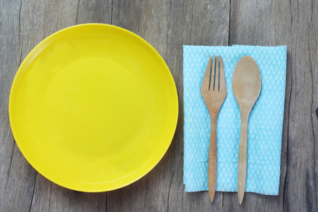 Top view yellow dish wooden spoon and cloth placed on a brown wooden floor for design in your work.の写真素材
