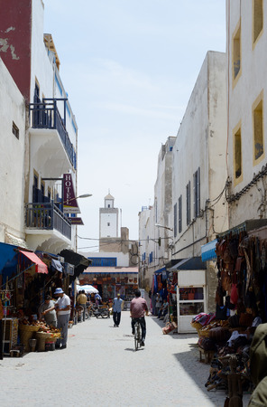ESSAOUIRA, MOROCCO - MAY 14, 2014  Local berbers walking in shopping street with tower in scene  Essaouira, Morocco  May 14, 2014 のeditorial素材