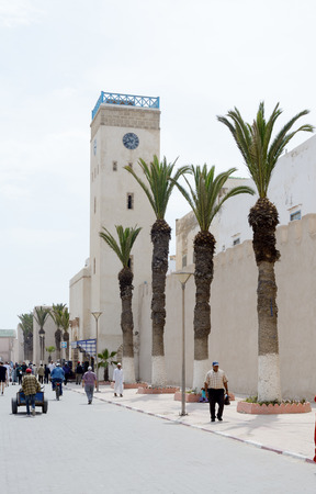 ESSAOUIRA, MOROCCO - MAY 14, 2014  Local berbers walking outside of citadel walls showing clock tower and palm trees  Essaouira, Morocco  May 14, 2014 のeditorial素材