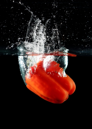 sweet pepper drop into water on black background の写真素材