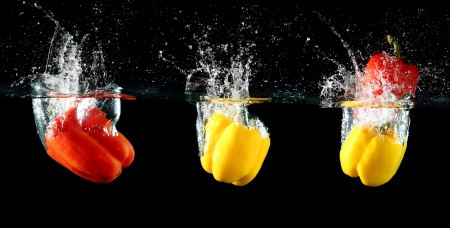 sweet pepper drop into water on black background の写真素材