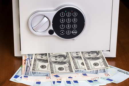 Safe with euro and dollars on wooden shelf