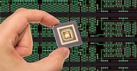 Microprocessor in hand in front of chip layoutの写真素材