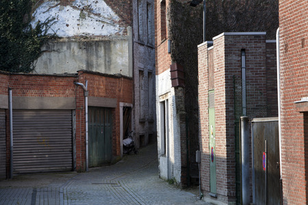 Garage doors and a small dark alley in a residential district of Mechelen in Belgium. It's an old but clean neighborhood with a no parking zone.の写真素材