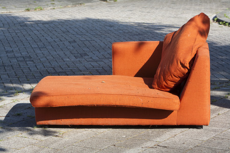 Abandoned old orange couch in the street