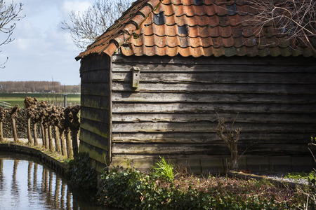 Old roof tile barn  with a birdhouse next to the waterの写真素材