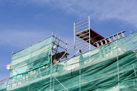 Scaffolding protection nets with green and blue skyの写真素材