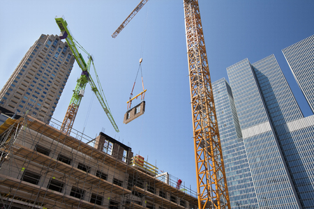 Crane lifting a wall on a construction site in Rotterdam with the Rem Koolhaas building in the backgroundの写真素材