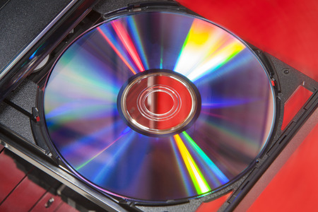 DVD disc in player of a desktop computer with a red backgroundの写真素材