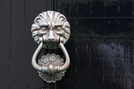 Antique lion door knocker on a black wooden door in the Netherlandsの写真素材