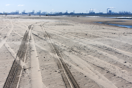 Tire tracks on the dutch beach and Rotterdam industry in the backgroundの写真素材