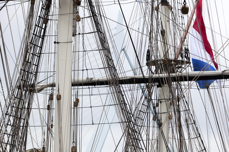 Rigging of a historical sailing ship with a dutch flag and the Rotterdam Erasmus bridge in the...