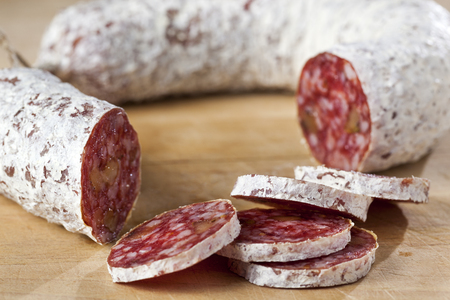 Closeup of a delicious dry sausage with walnuts on woodの写真素材