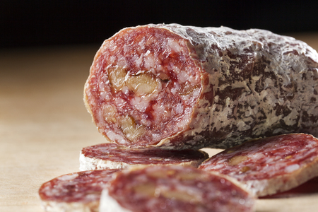Closeup of a delicious dry sausage with walnuts on woodの写真素材