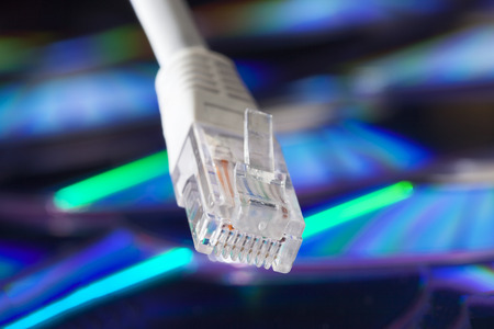 Closeup of a network plug and cable with a pile of cds technical backgroundの写真素材