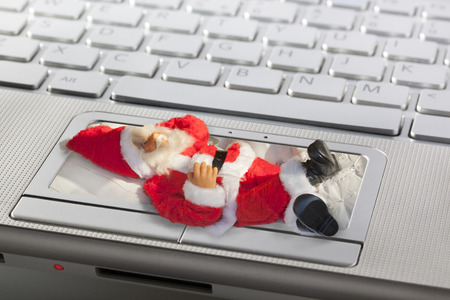 Santa Claus sleeping on the touchpad of a laptopの写真素材