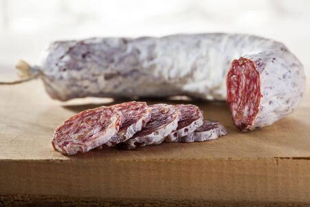 Sliced delicious dry sausage on a wooden cutting board