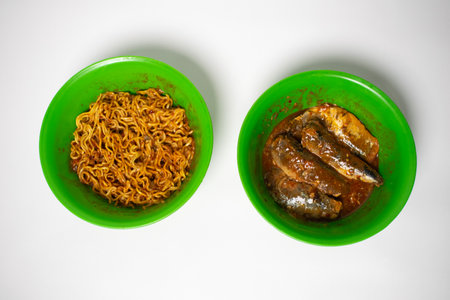 Green plastic bowl filled with sardines and fried noodles. The background is white.の写真素材
