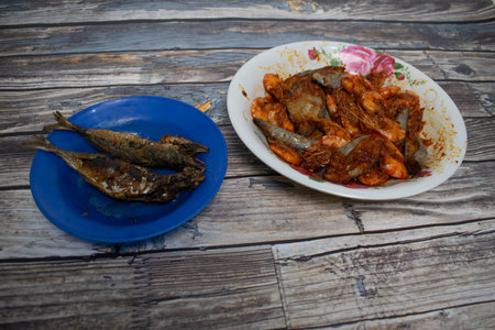 Freshly fried chili prawns and fish are placed on a plate, ready for a delicious seafood meal.の写真素材