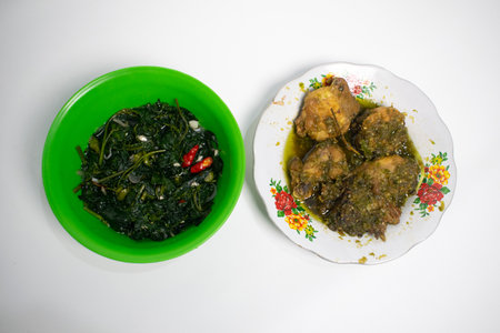 A delicious dish of green sauce chicken served with a bowl of vegetables.の写真素材