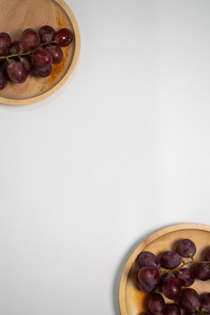 Sweet red grapes on a light wooden plate, perfect for a healthy snack.の写真素材