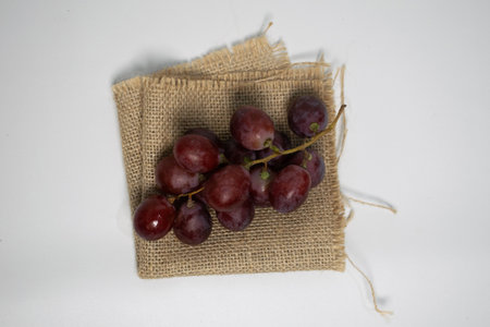 A bunch of juicy grapes resting on textured jute cloth, perfect for organic vibes.の写真素材