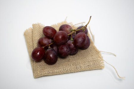 Fresh red grapes placed on a rustic piece of burlap fabric, simple and natural.の写真素材