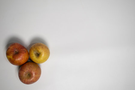 Three apples arranged on a white surface, forming a simple and natural composition.の写真素材