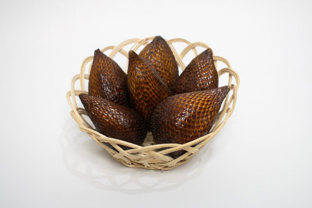 A woven basket filled with fresh salak (snake fruit), known for its scaly brown skin and sweet, tangy flavor.の写真素材