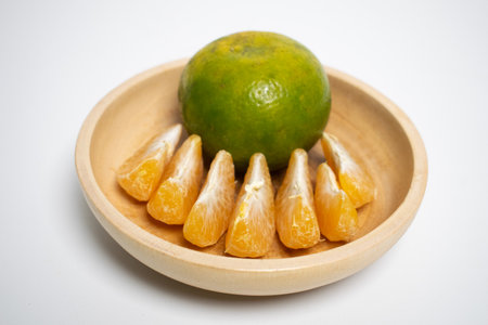 Citrus fruit neatly arranged in a wooden bowl on a white background.の写真素材