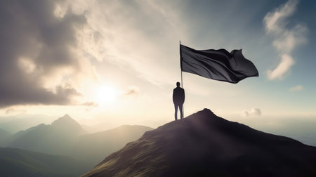 A silhouette of a successful businessman stands with a large flag on top of a mountain in the morning sunlight, featuring his successの素材