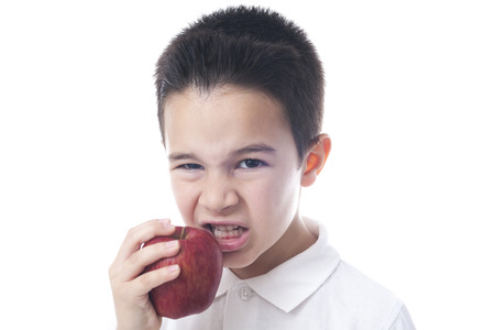 Child eats an apple with angry face.の写真素材