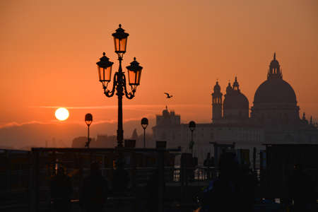 Silhouette of a street lamp at sunset in Venice, Italyの写真素材