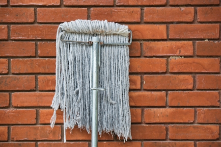 dirty mop against the orange brick wall の写真素材