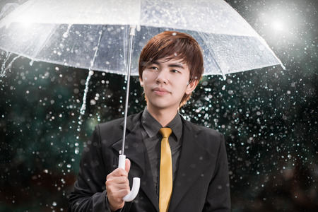 Smart business man holding umbrella among the rainの写真素材