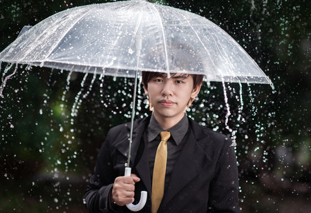 Smart business man holding umbrella among the rainの写真素材