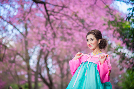 Hanbok  the traditional Korean dress and beautiful Asian girl with sakuraの写真素材