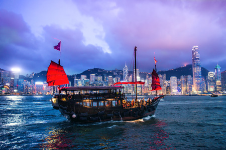 HONG KONG - JUNE 09, 2015: A Chinese traditional junk boa sailing passing famous Hong Kong skyline. JUNE 09, 2015. They provides popular cross harbor tours for tourists.のeditorial素材