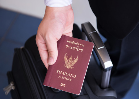 Hand holding Thai passport, ready to travelの写真素材