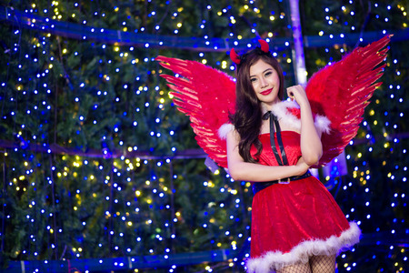 Portrait of beautiful young Santa woman on bright lights backgroundの写真素材