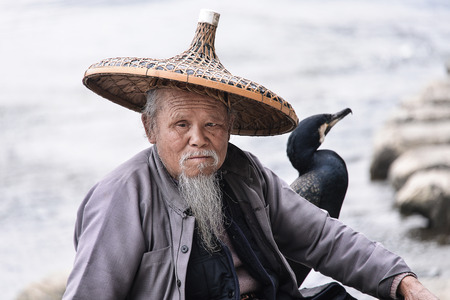XINGPING, CHINA - MARCH 02, 2016: Cormorant fisherman sits on the ancient bamboo rafting - The Li River, Xingping, China.のeditorial素材