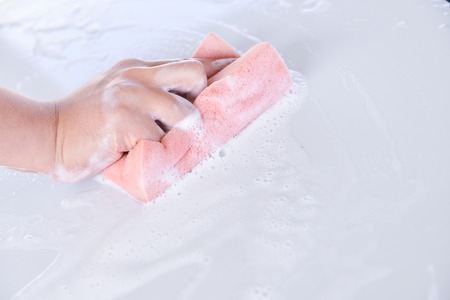 man washing a soapy white car with a pink spongeの写真素材